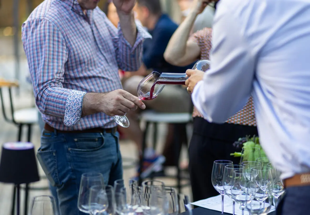 Sommelier versant du vin rouge depuis une carafe dans un verre à pied lors d'une dégustation pour un mariage.
