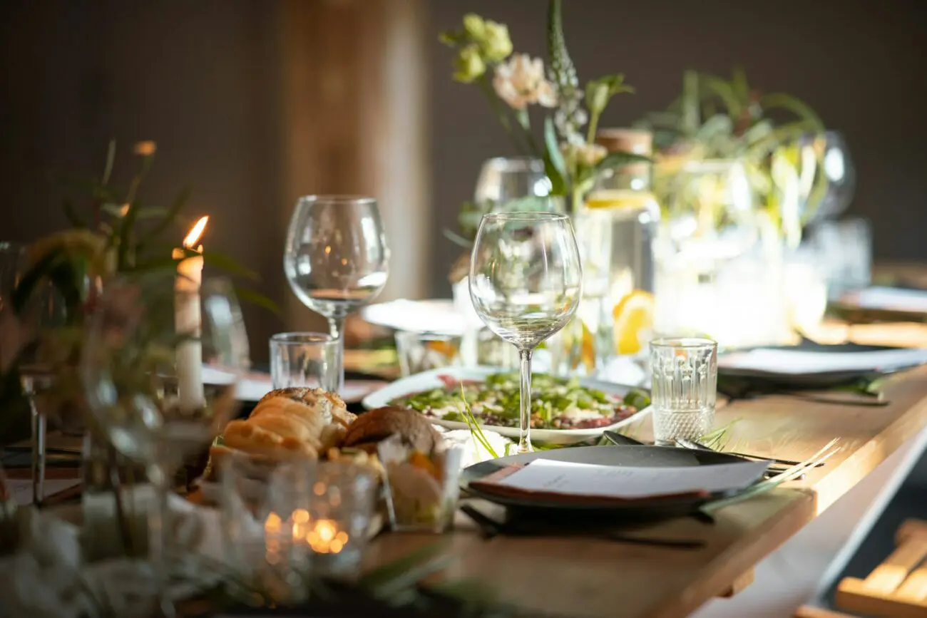 Table de mariage champêtre en bois avec décoration naturelle, bougies allumées, verres à vin élégants et fleurs des champs pour un dîner de noces convivial.