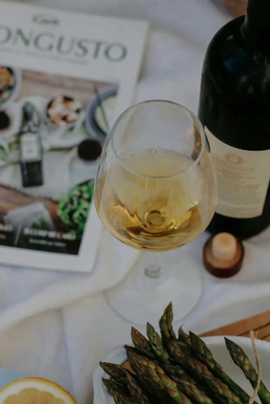 Inspiration menu de mariage : asperges vertes fraîches, verre de vin blanc et bouteille sur nappe blanche, par vins-mariages.net