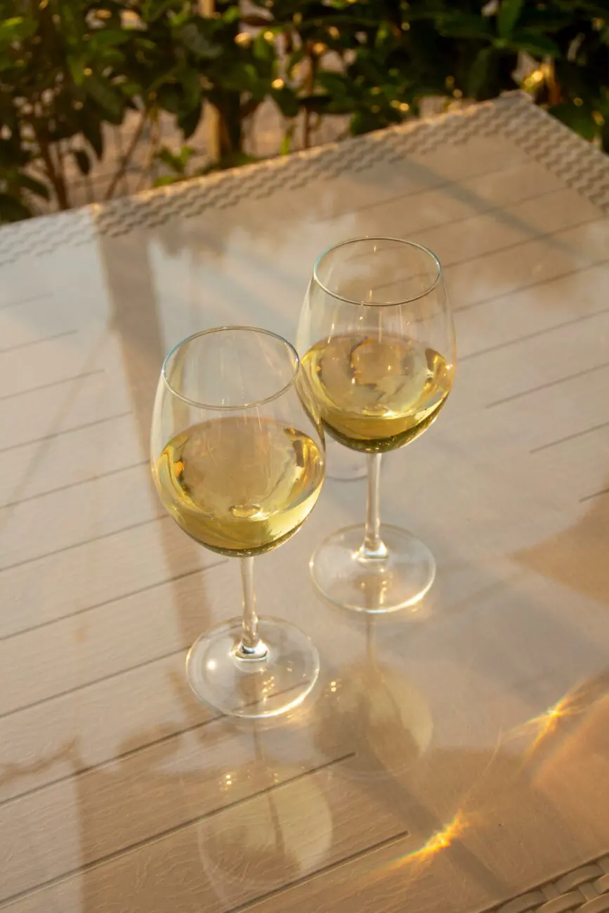 Deux verres de vin blanc servis sur une table en terrasse lors d'un vin d'honneur de mariage ensoleillé.