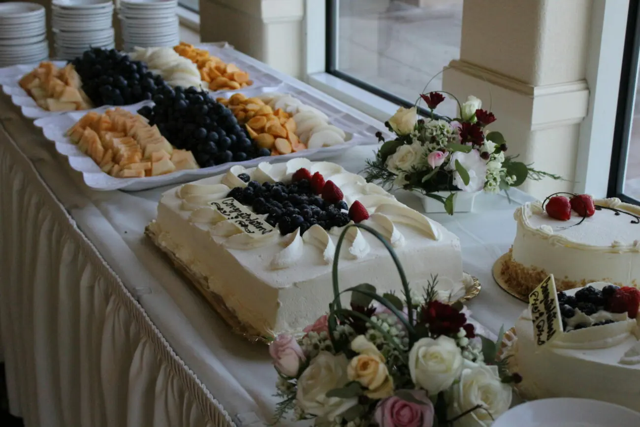 Buffet de desserts de brunch de mariage avec gâteaux à la crème, fruits frais et fleurs, accompagné de vins moelleux de vins-mariages.net.