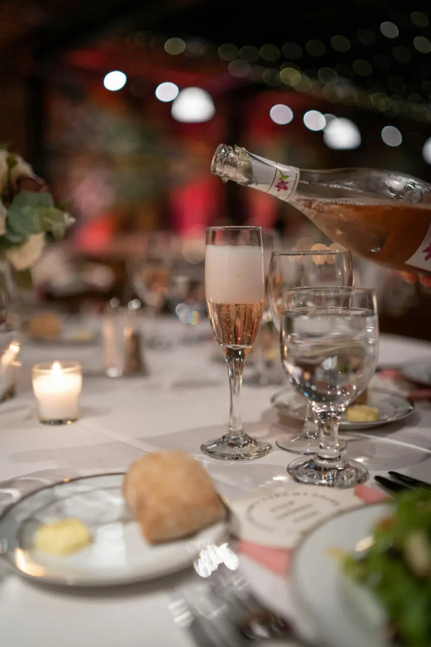 Verre de champagne ou vin mousseux rosé en train d'être servi sur une table de fête de mariage.