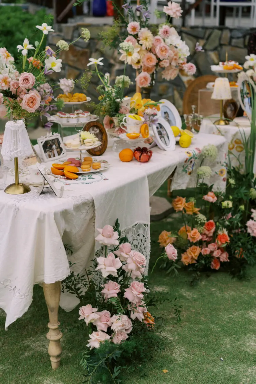 Table de brunch de mariage romantique en extérieur avec décoration florale rose, macarons et agrumes, un cadre idéal pour les vins de vins-mariages.net.