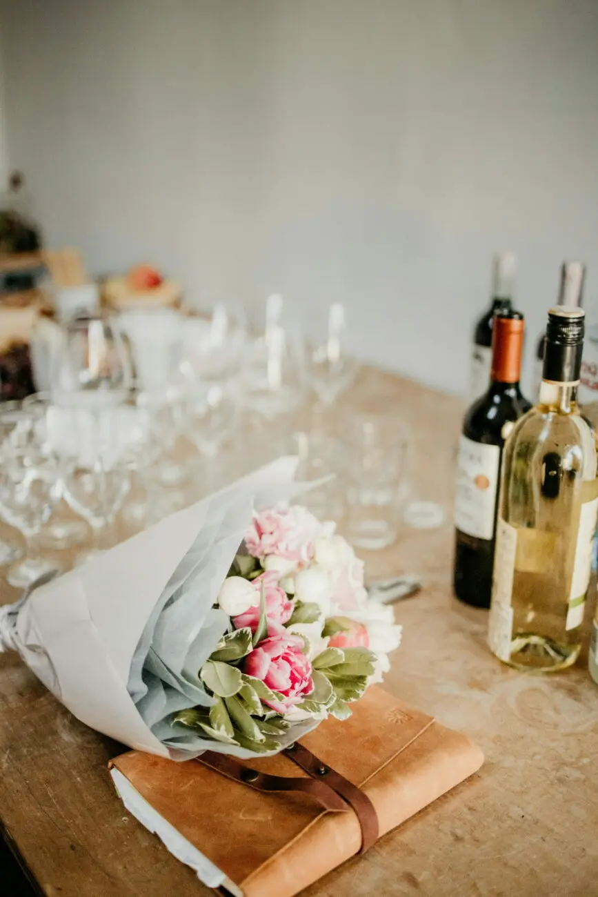 Bouteille de vin rosé et bouquet de fleurs sur une table de réception de mariage, une sélection vins-mariages.net pour le vin d'honneur.