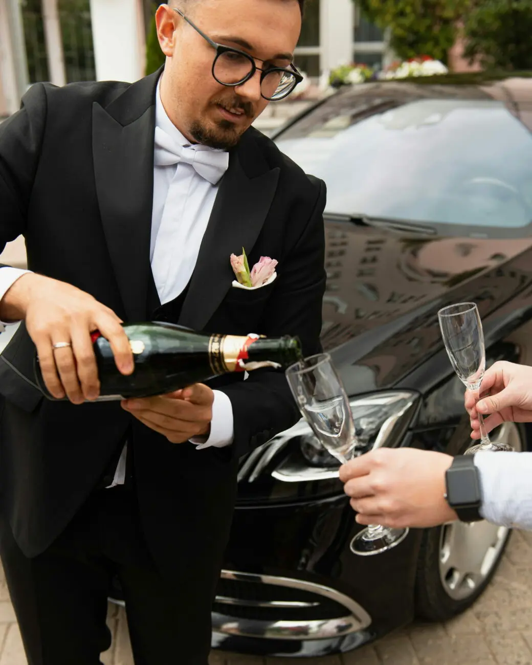 Service d'un champagne d'exception pour un vin d'honneur de mariage devant une voiture de prestige.
