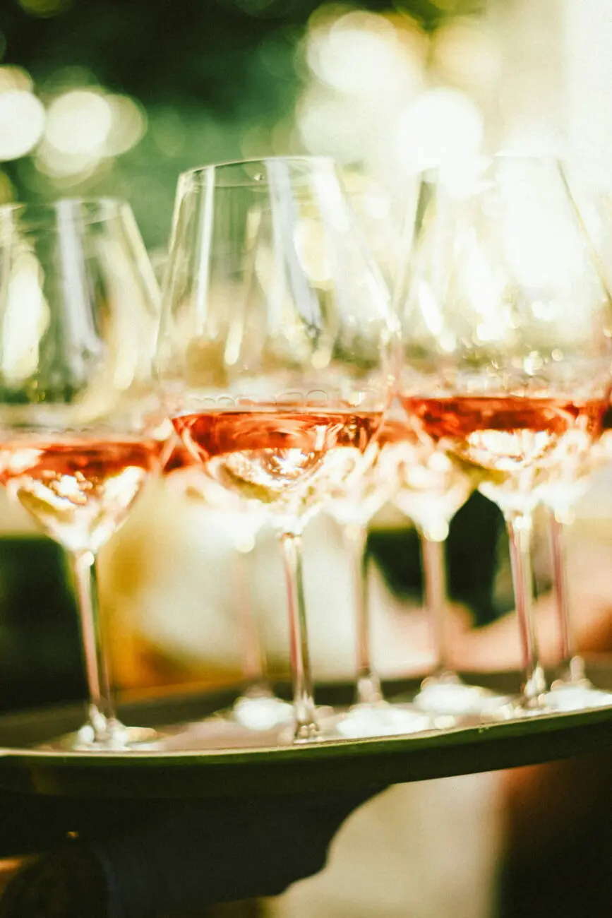 Plateau de verres de vin rosé servis lors d'une réception de mariage en plein air, une prestation signée vins-mariages.net.