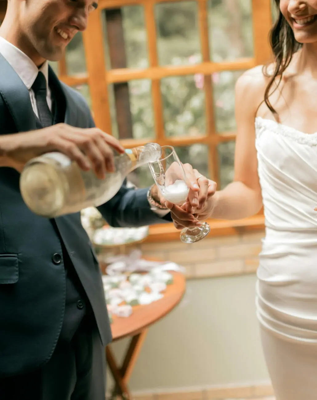 Un marié versant du champagne dans la flûte de la mariée lors de leur réception, une sélection de bulles par vins-mariages.net.