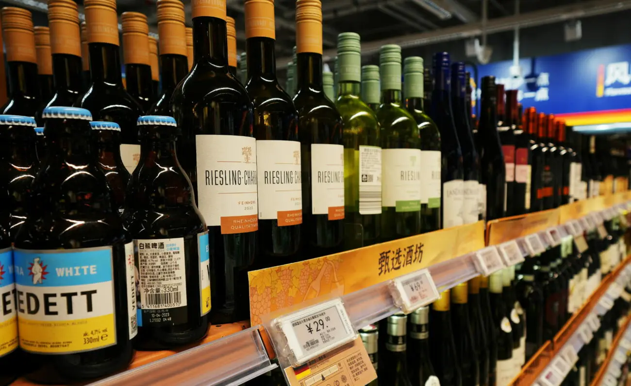 Gros plan sur des bouteilles de vin blanc Riesling alignées sur l'étagère d'un supermarché avec étiquettes de prix.