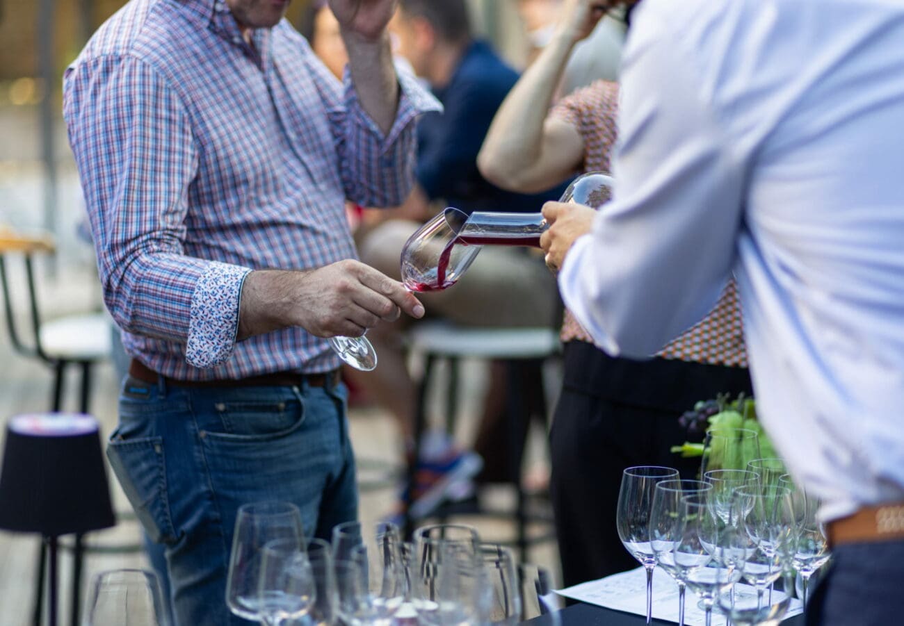 Sommelier versant du vin rouge depuis une carafe dans un verre à pied lors d'une dégustation pour un mariage.