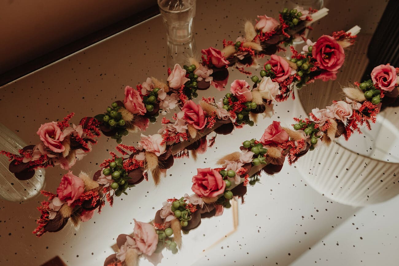 Bracelets de fleurs fraîches ou boutonnières de mariage composés de roses roses et de baies rouges sur un plateau miroir.