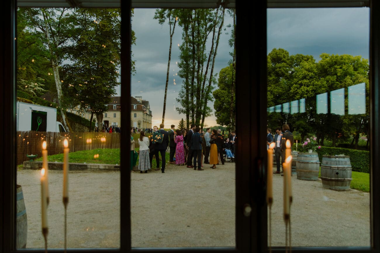 Vue sur une réception de mariage en extérieur dans un domaine viticole avec tonneaux de vin, sélection de vins de propriété.