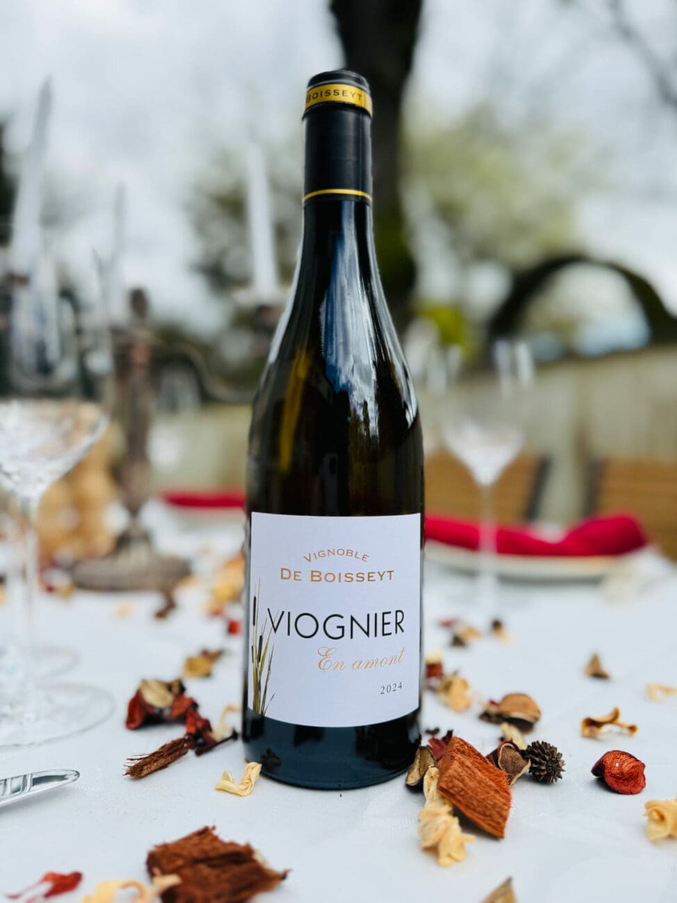 Bouteille de Viognier En Amont 2024 Vignoble de Boisseyt sur une table dressée avec pétales séchés en extérieur.