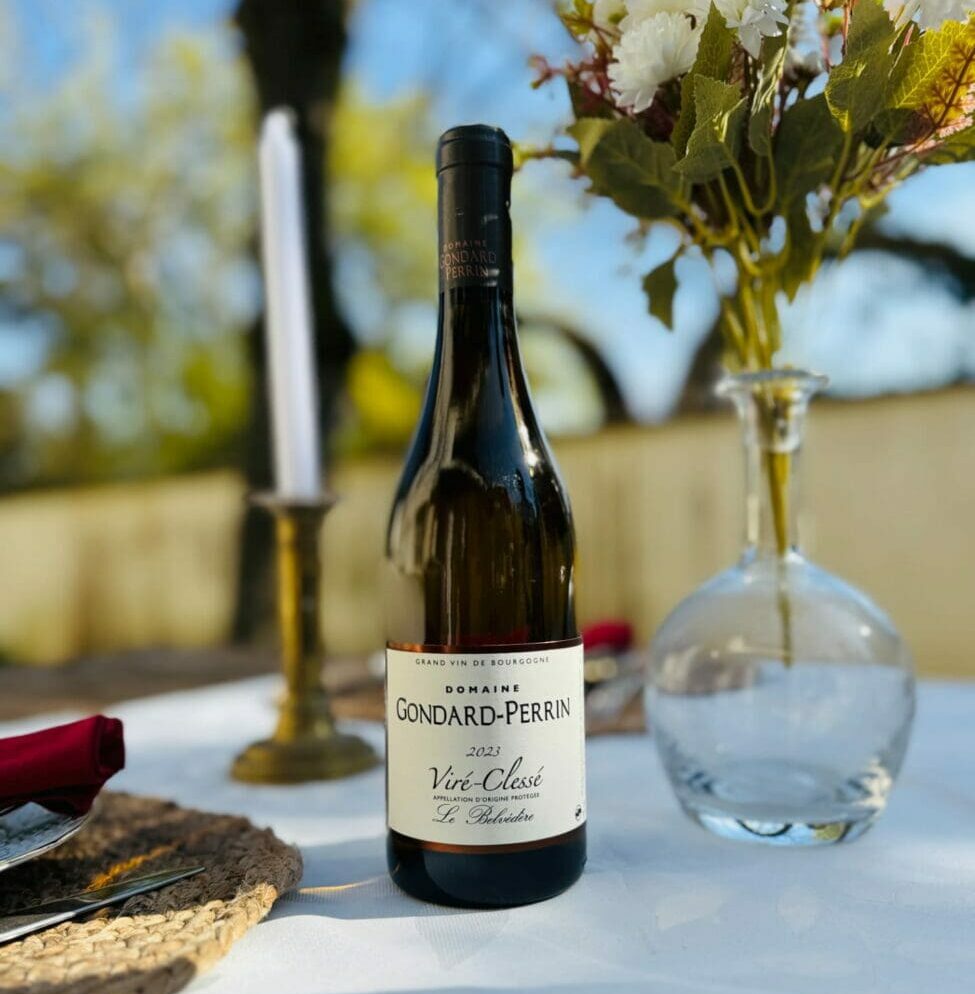 Bouteille de vin blanc Viré-Clessé "Le Belvédère" 2023 du Domaine Gondard-Perrin sur une table de mariage dressée avec nappe blanche, bougeoir et fleurs.