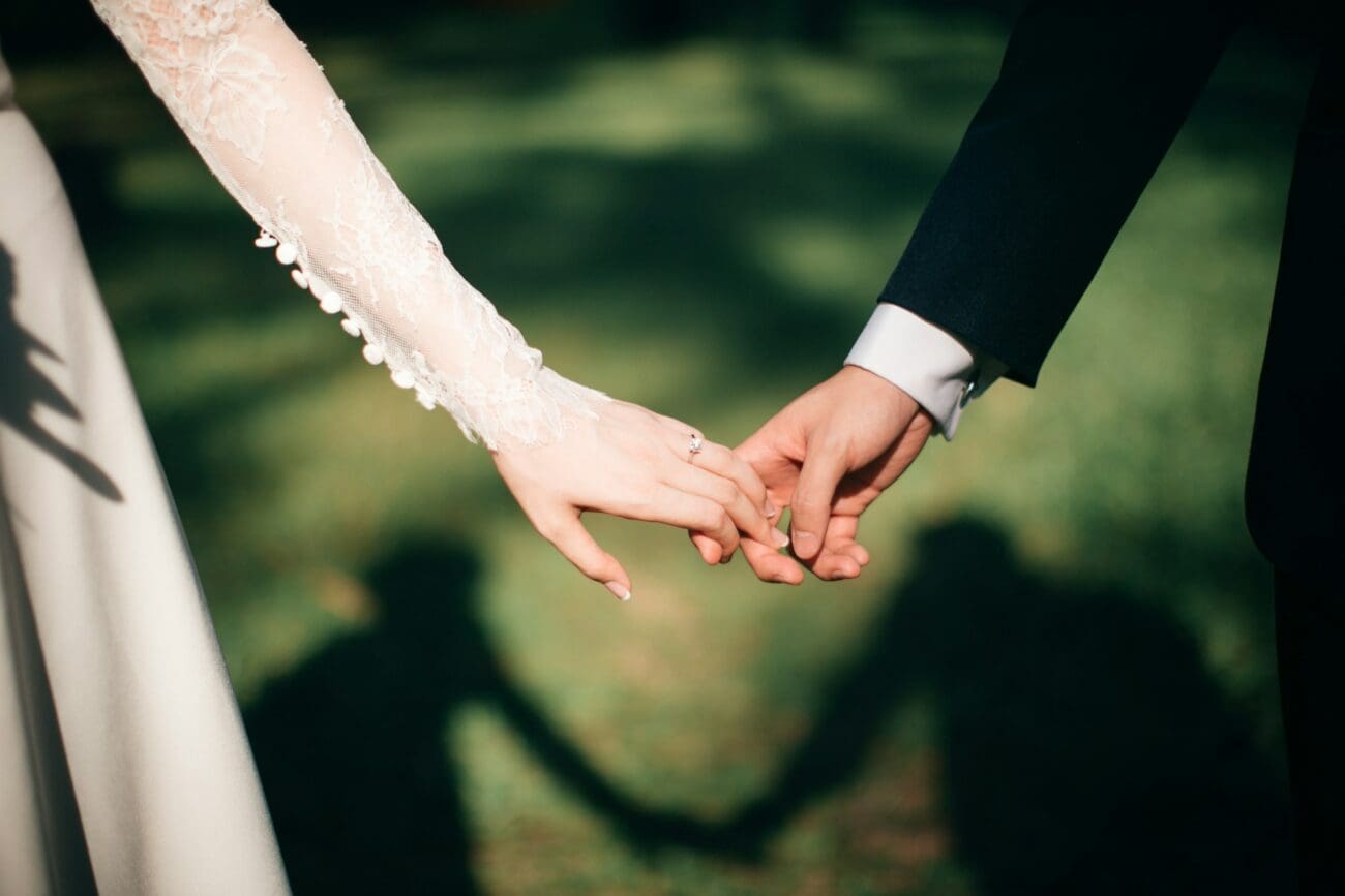 Mains d'un couple de mariés se tenant par la main en extérieur lors d'une réception de mariage champêtre.