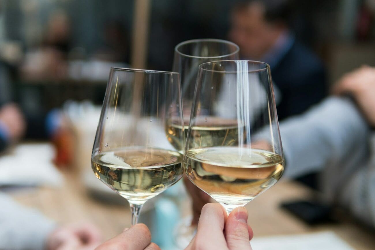 Invités de mariage trinquant avec des verres de vin blanc frais lors d'un vin d'honneur. Gros plan sur des verres à vin élégants et robe dorée du vin pour une réception de mariage.