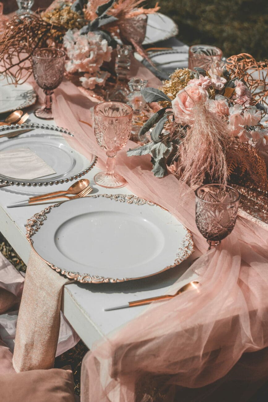 Décoration de table de mariage élégante avec verres ciselés et fleurs roses, prête pour la sélection de vins de vins-mariages.net.