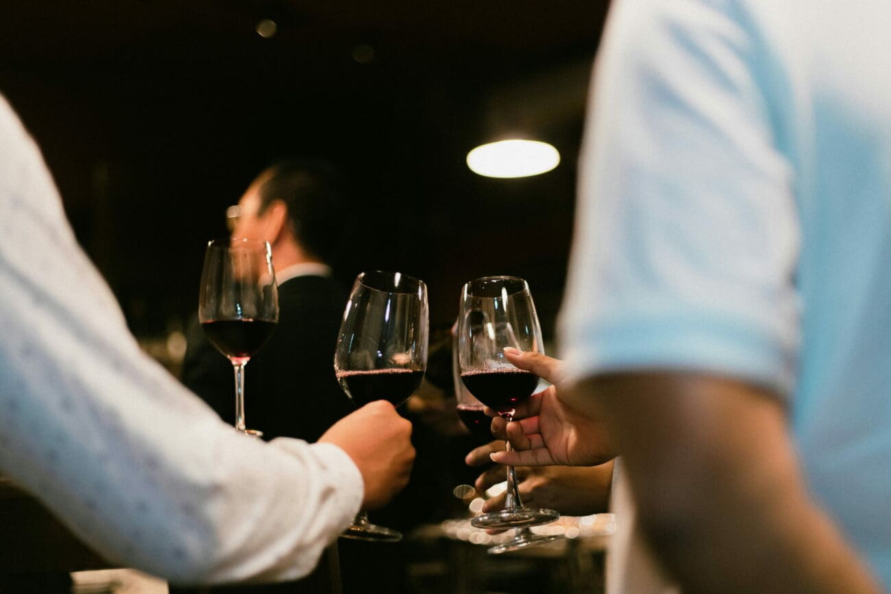 Groupe d'invités portant un toast avec des verres de vin rouge lors d'une soirée de mariage en intérieur.