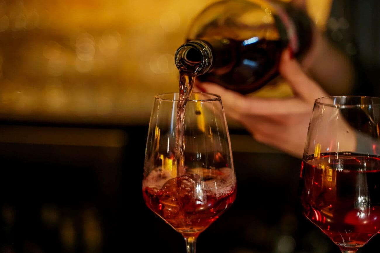 Mouvement du vin rouge versé dans un verre en cristal avec des reflets dorés et une ambiance tamisée en arrière-plan.