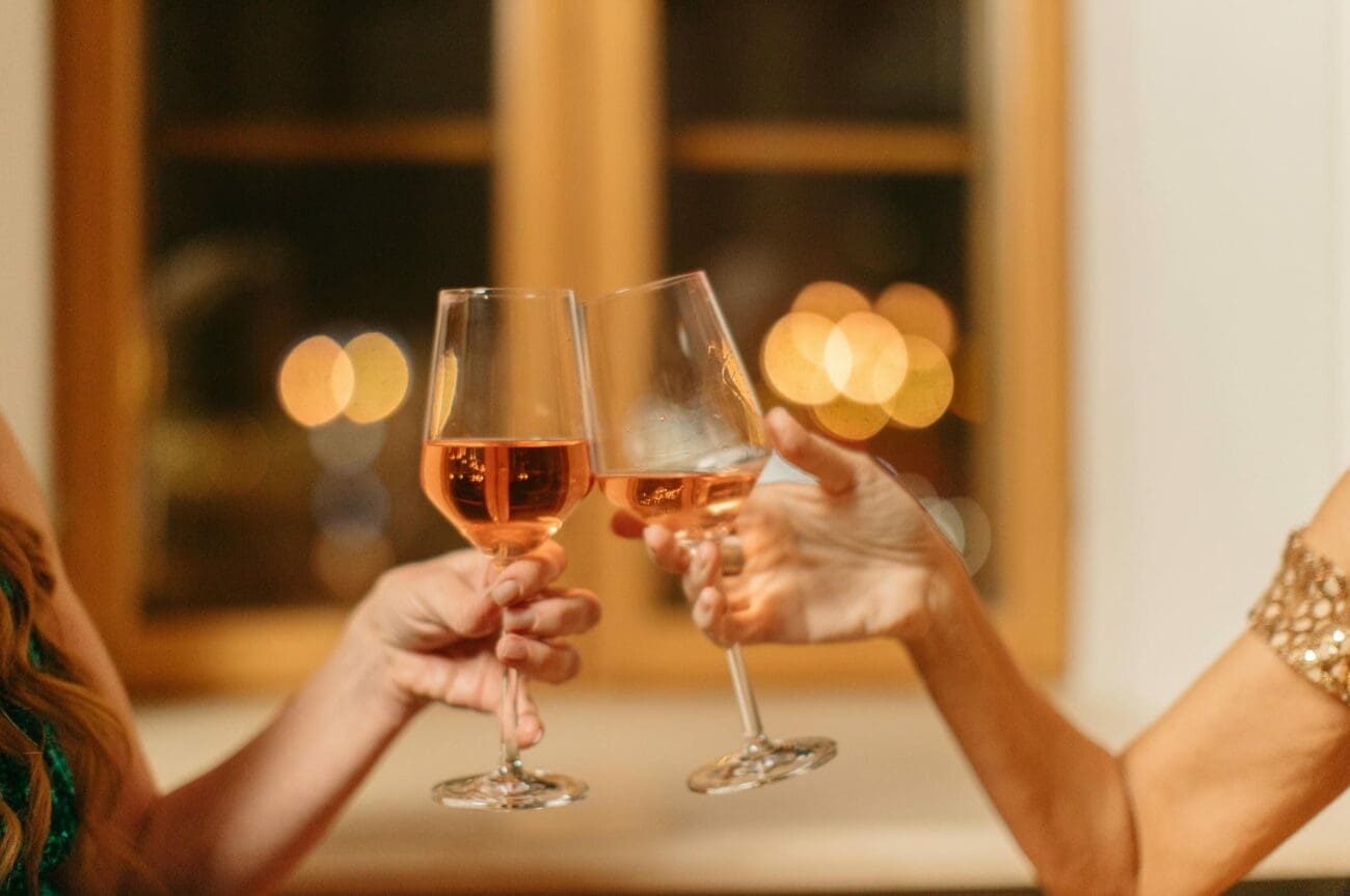 Deux invitées trinquent avec des verres de vin rosé lors d'une soirée de mariage festive, une sélection vins-mariages.net.