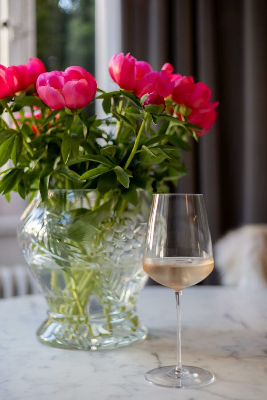 Décoration de table de mariage avec un bouquet de pivoines roses et un verre de vin rosé de Provence, sélection vins-mariages.net.