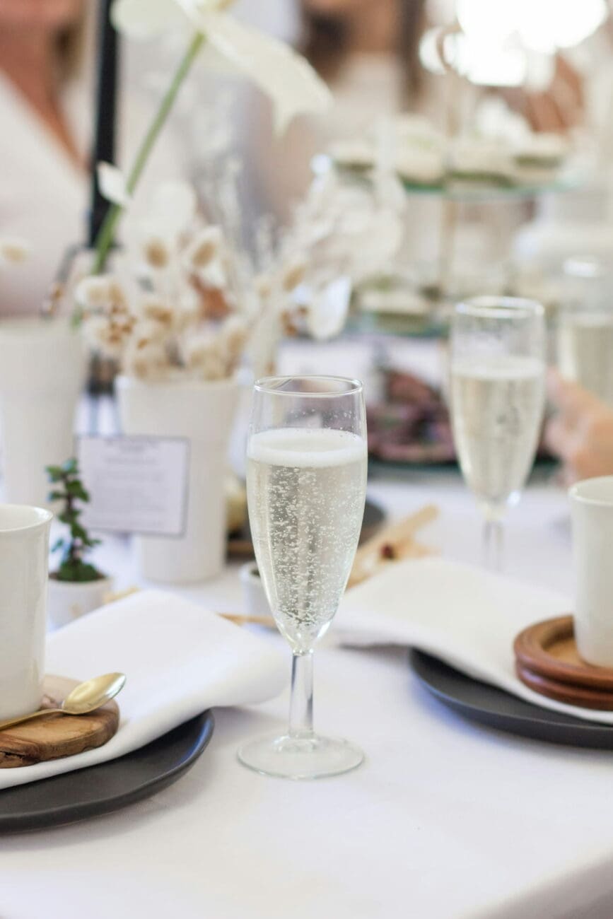 Une flûte de champagne effervescent sur une table de brunch de mariage chic et minimaliste, avec une sélection de vins de vins-mariages.net suggérée.