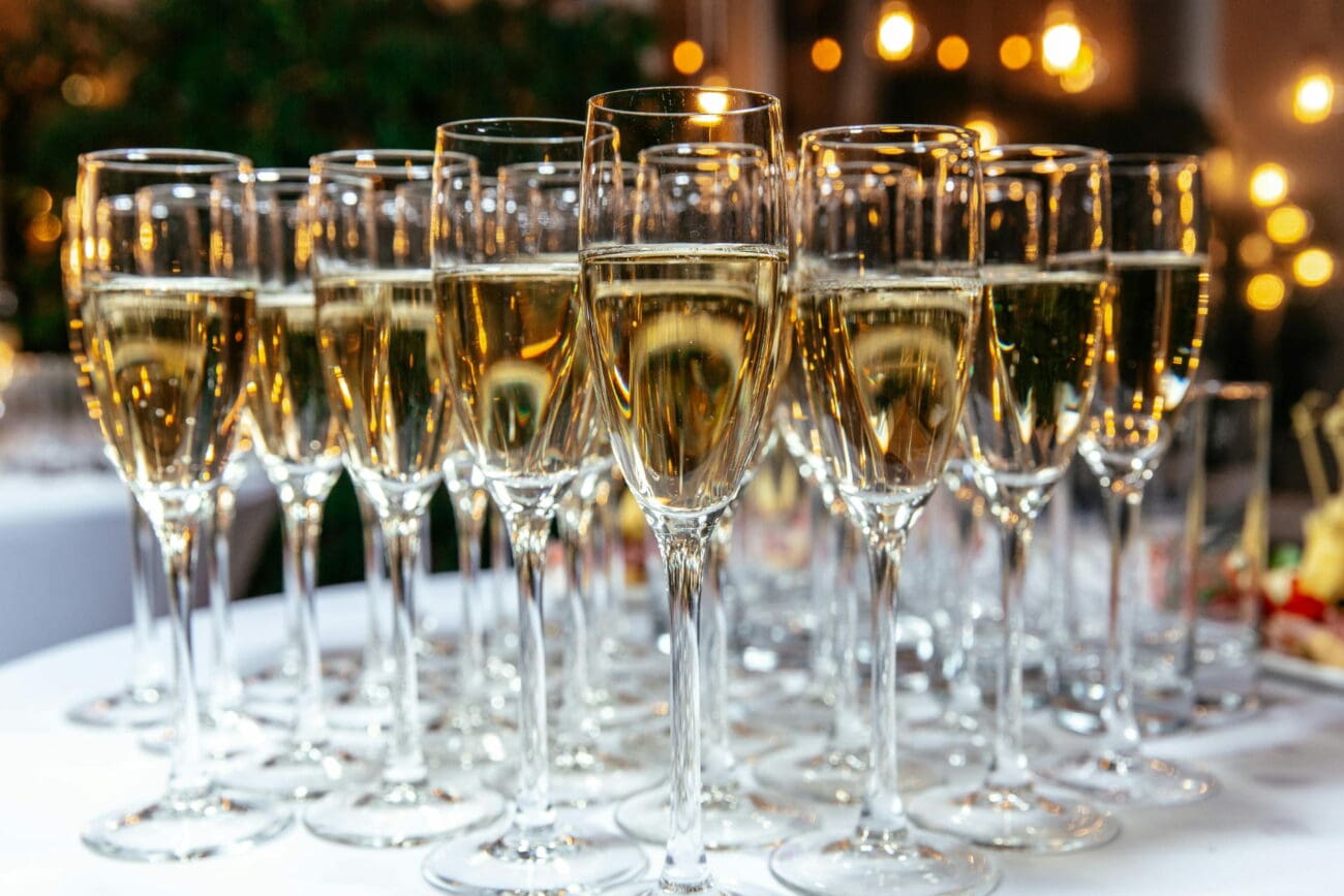 Alignement de flûtes de champagne et de vins pétillants sur un buffet de mariage éclairé, une sélection vins-mariages.net.