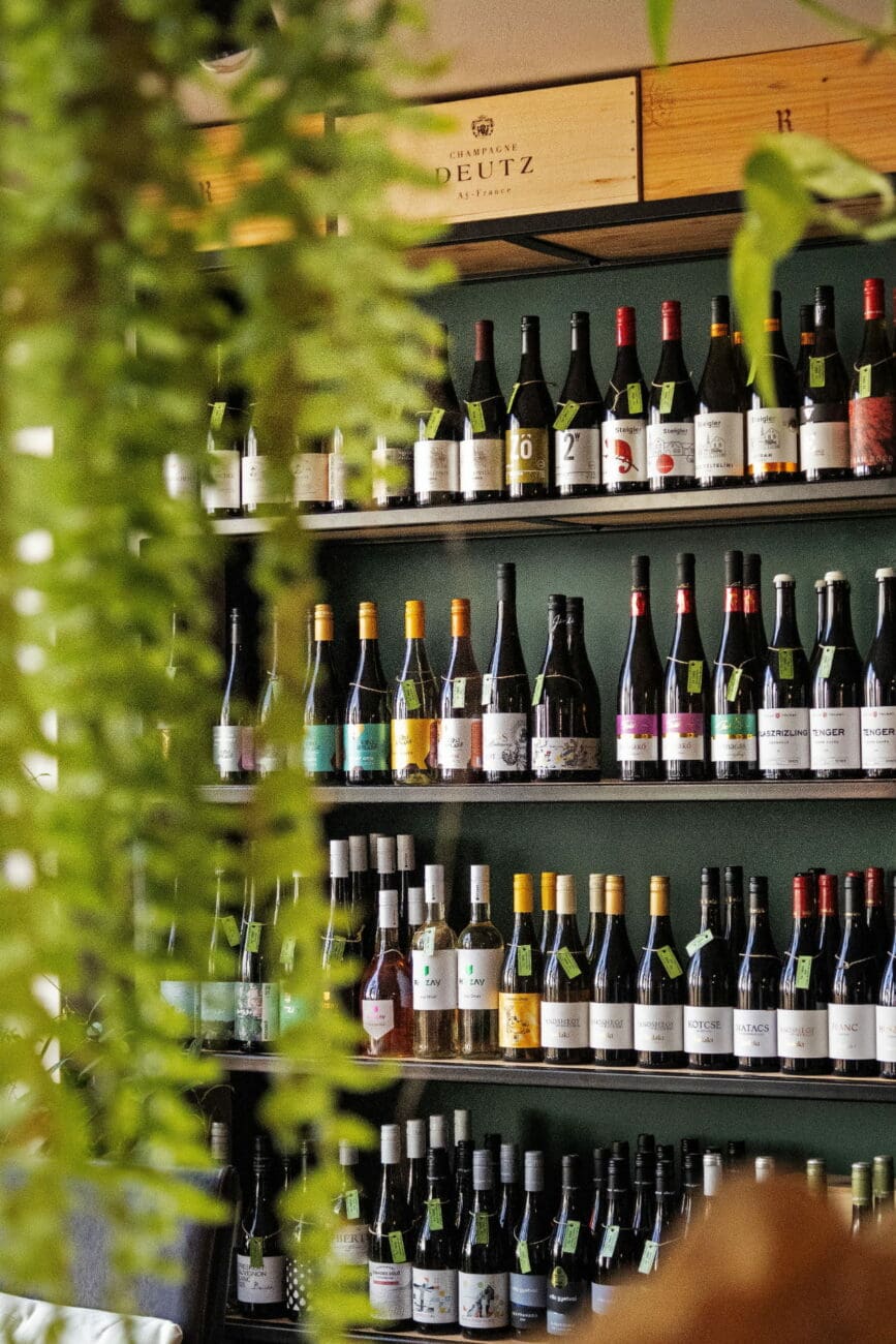 Étagères en bois d'une cave de caviste moderne alignant plusieurs bouteilles de vin et caisse de champagne.