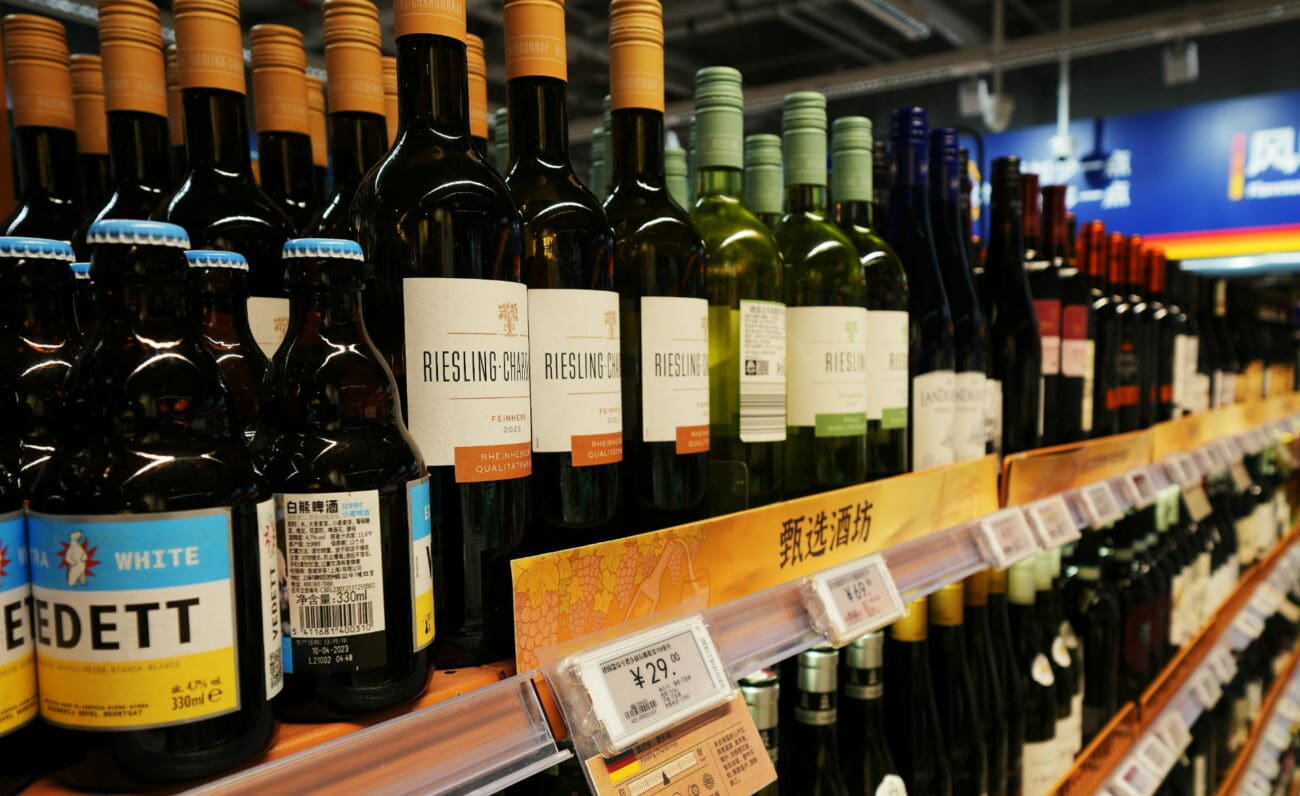 Gros plan sur des bouteilles de vin blanc Riesling alignées sur l'étagère d'un supermarché avec étiquettes de prix.